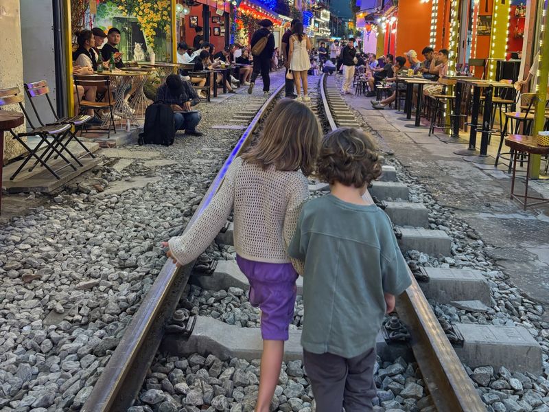 Deux enfants marchant sur les rails de la rue du train illuminée à Hanoï