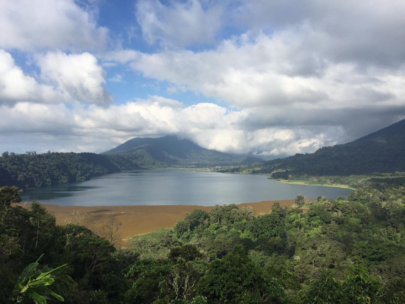 Un lac de cratère entouré de forêt, sous les nuages