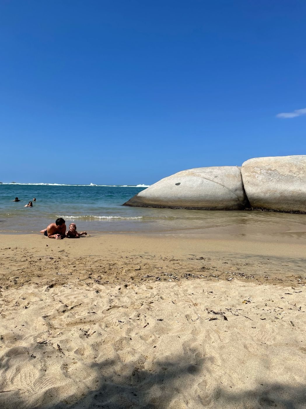 Papa et notre fille allongés au bord de l'eau sur une plage du parc Tayrona