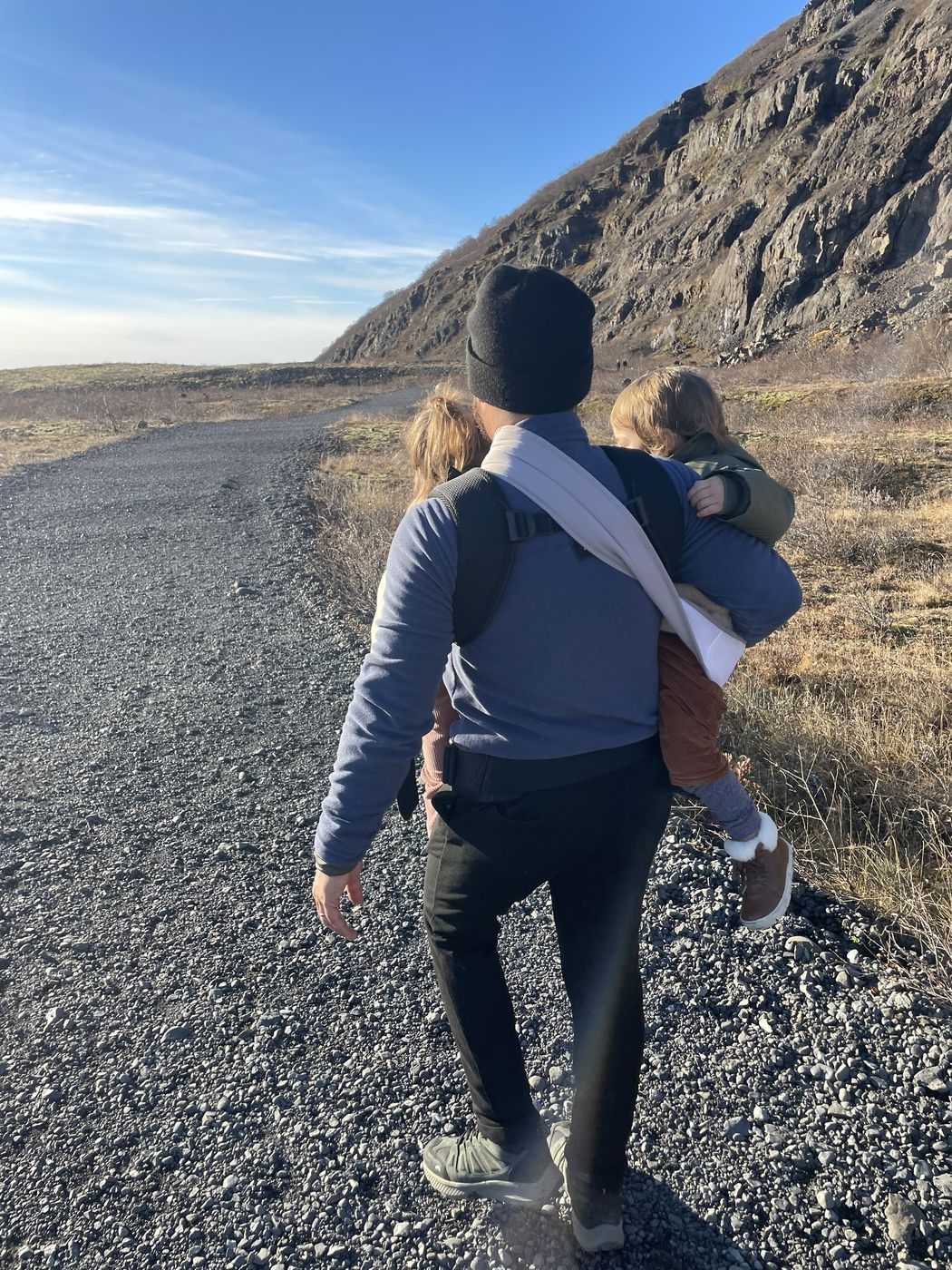 Papa qui porte nos deux enfants sur le chemin du glacier