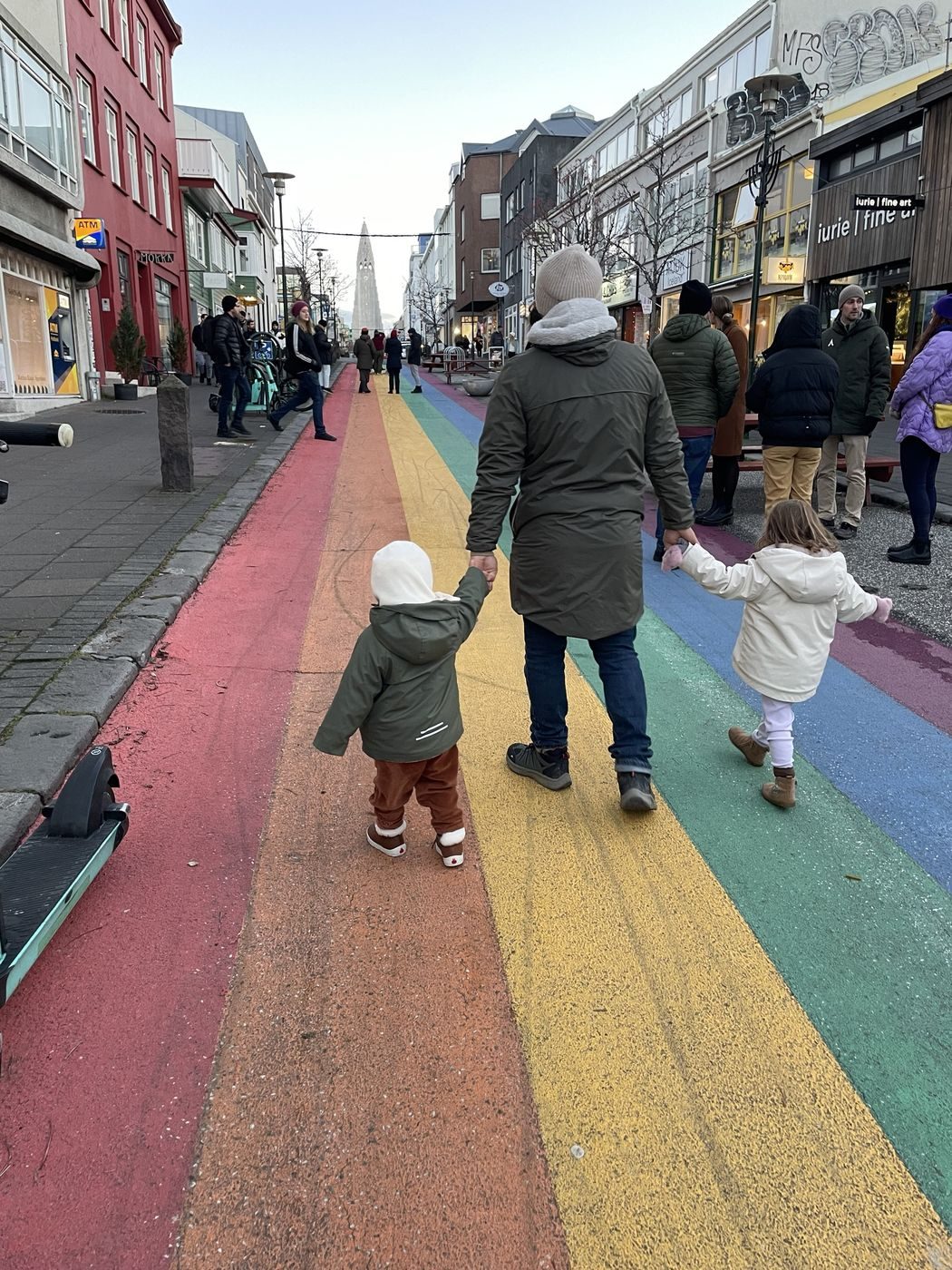 Papa et nos deux enfants main dans la main sur la rue arc-en-ciel de Reykjavík
