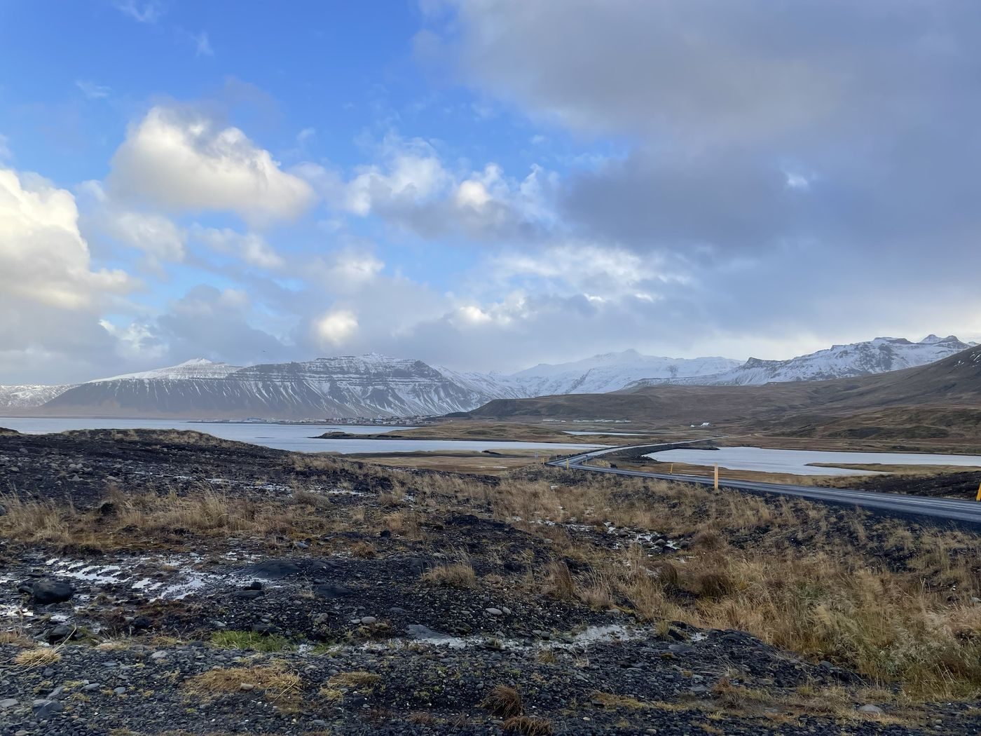 Une route qui longe un fjord au pied des montagnes enneigées