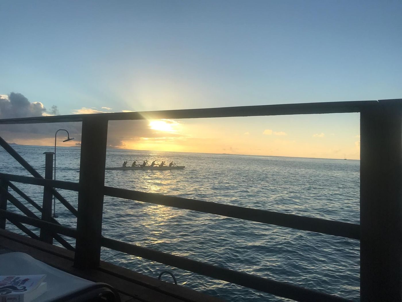 Une pirogue de rameurs qui glisse sur le lagon au coucher du soleil