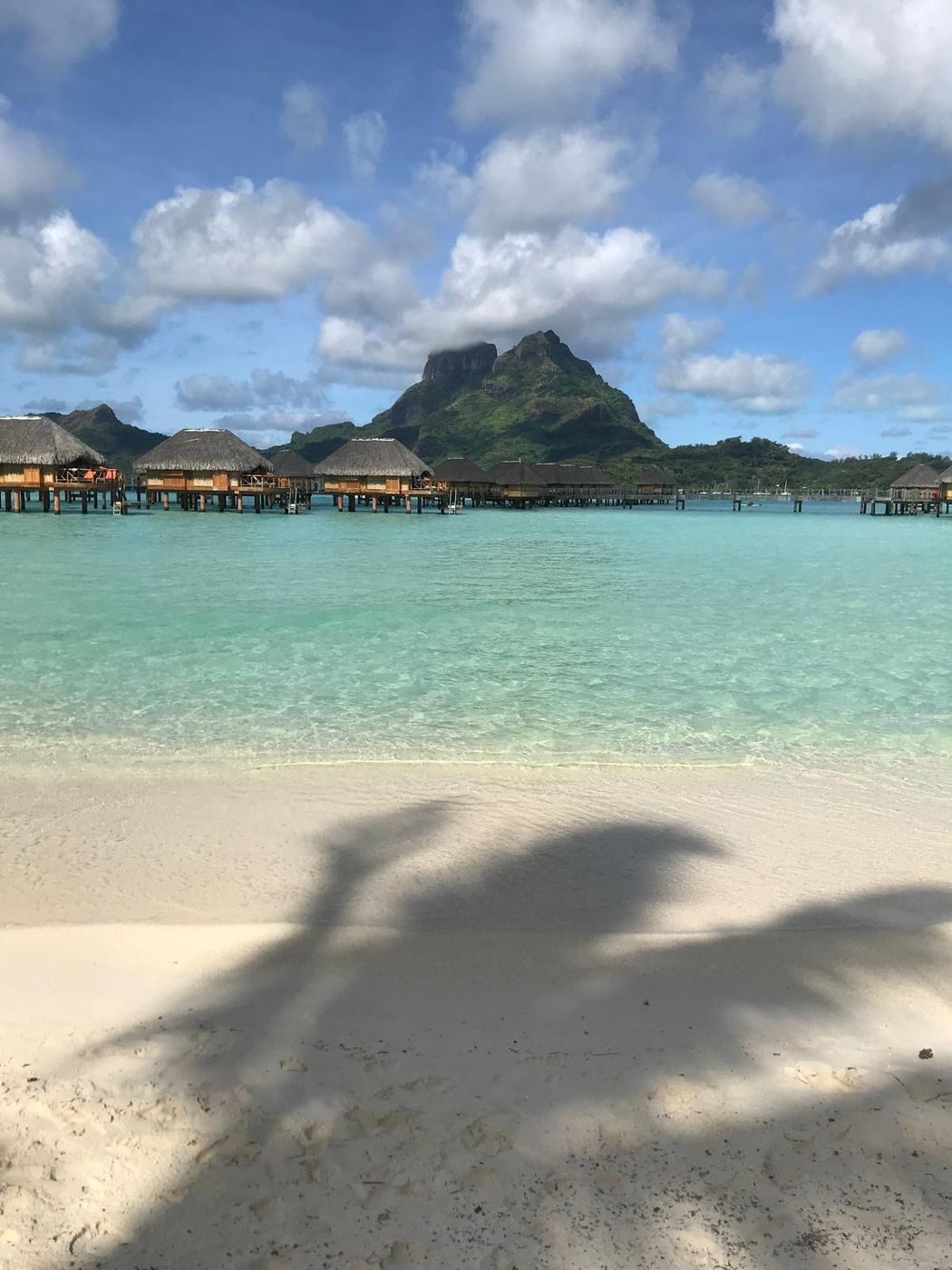 Bungalows sur pilotis et mont Otemanu depuis une plage de sable blanc à Bora Bora