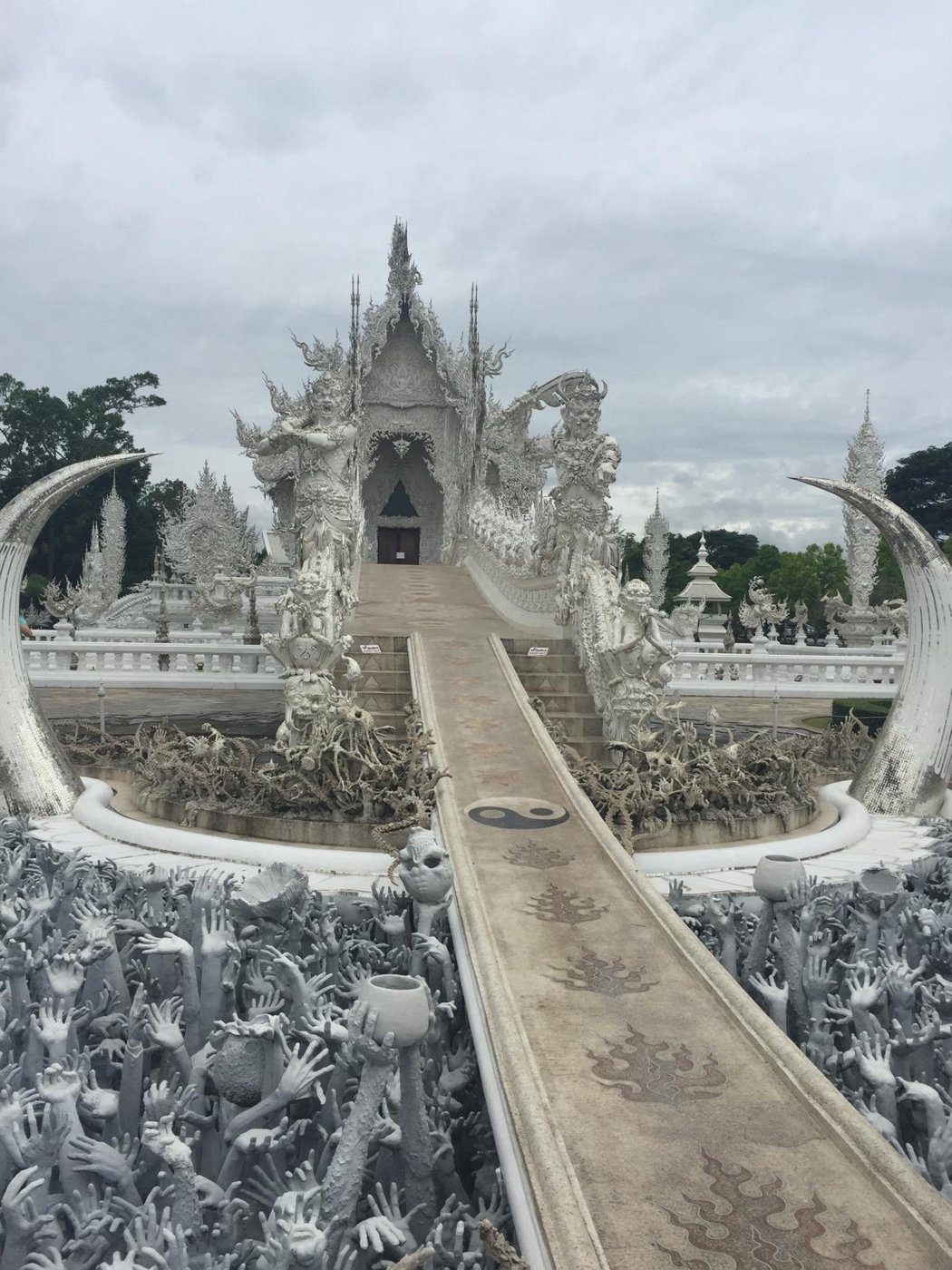 Le temple blanc de Chiang Rai et son pont au-dessus des mains sculptées