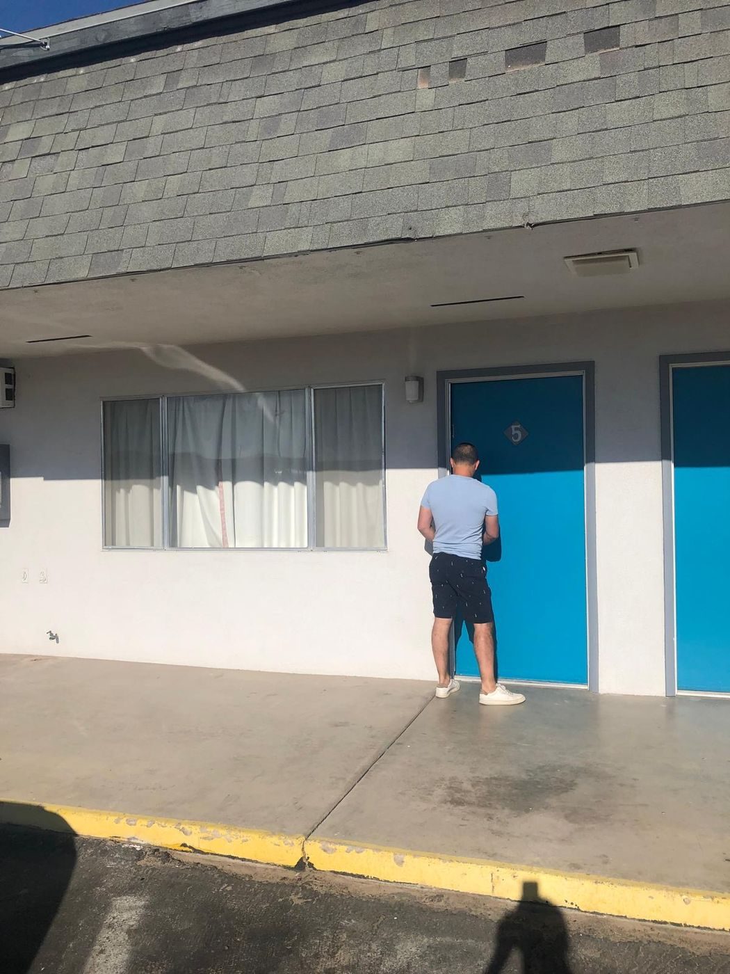 Devant la porte bleue d'un motel typique