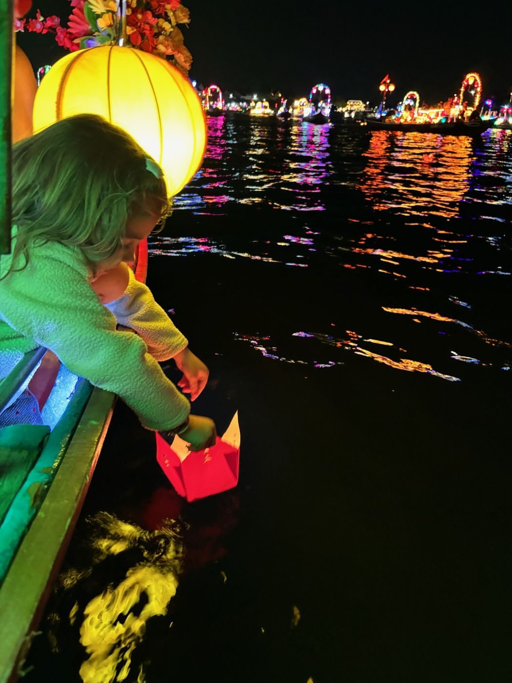 Notre fille dépose une lanterne sur la rivière illuminée de Hoi An