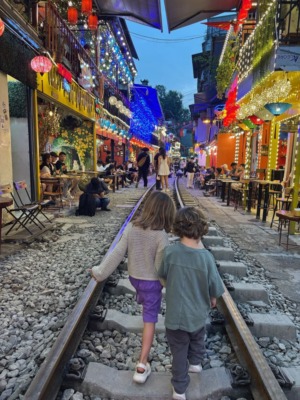 Nos deux enfants qui marchent sur les rails de la rue du train illuminée à Hanoï